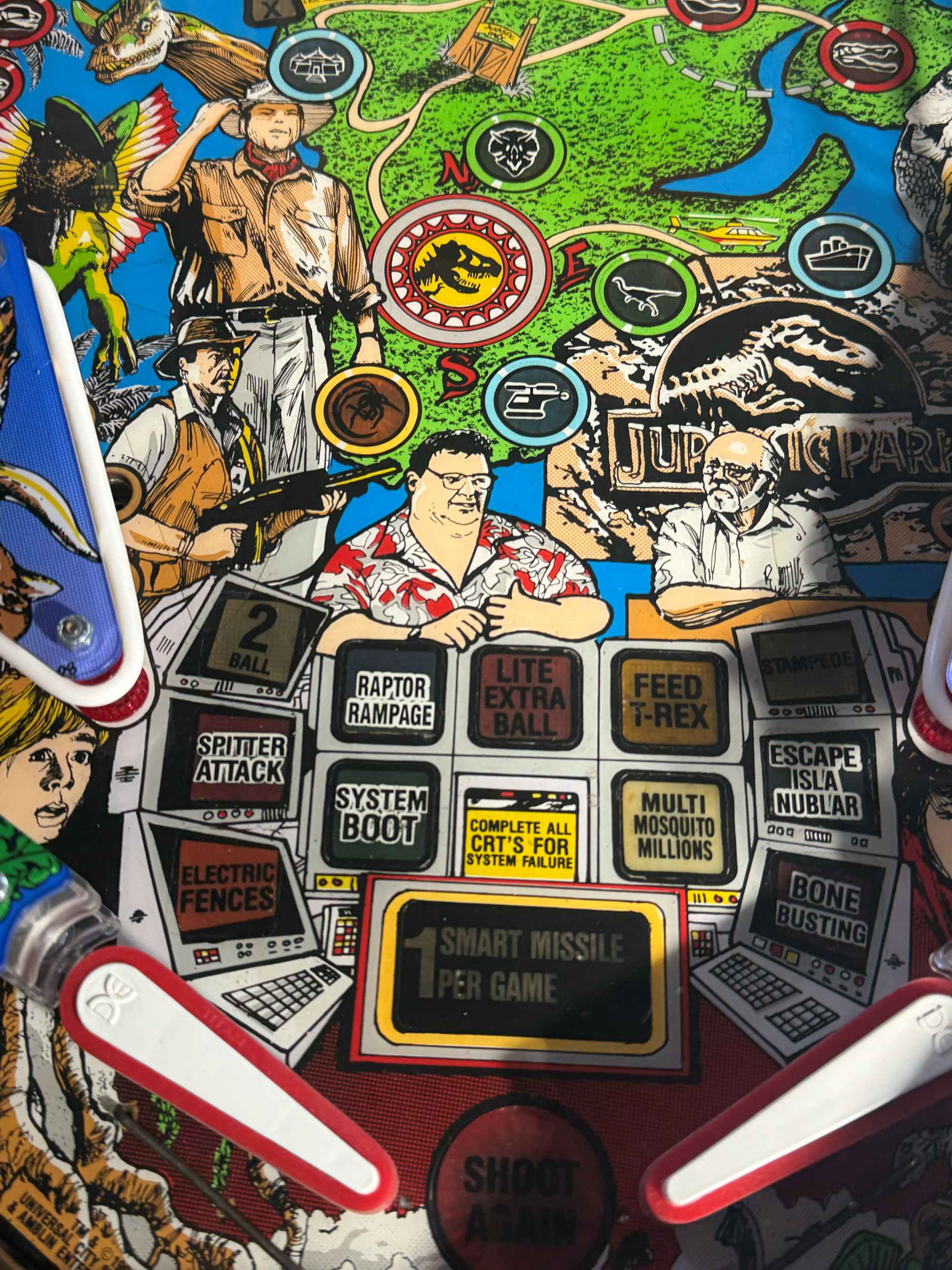 Close-up of Jurassic Park pinball machine with various characters and game elements.